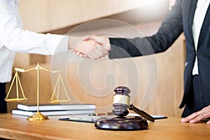 Gavel Justice hammer on wooden table with judge and client shaking hands after adviced in background at courtroom, lawyer service