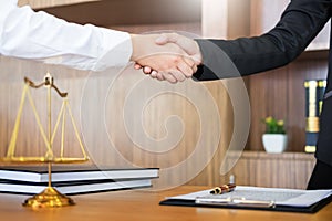 Gavel Justice hammer on wooden table with judge and client shaking hands after adviced in background at courtroom, lawyer service