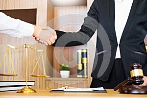 Gavel Justice hammer on wooden table with judge and client shaking hands after adviced in background at courtroom, lawyer service