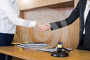 Gavel Justice hammer on wooden table with judge and client shaking hands after adviced in background at courtroom, lawyer service