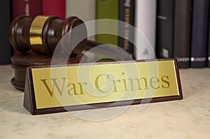 Gavel and law book with sign and war crimes on a wooden table