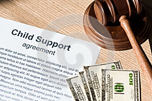 Gavel near document with child support agreement and dollar banknotes