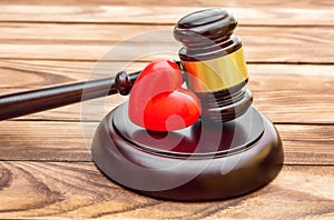 Gavel with red heart on wooden table. Close up