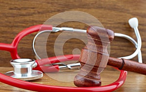 Gavel and red stethoscope on wood grain background