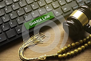 Gavel, rosary beads and computer keyboard written with Sharia Law