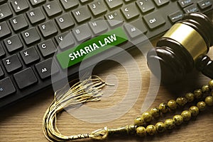 Gavel, rosary beads and computer keyboard written with Sharia Law photo