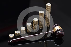 Gavel On Sounding Block In Front Of Stacked Coins