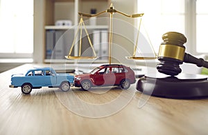 Gavel and two crashed toy cars on lawyer's or judge's table illustrating car insurance concept