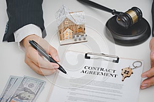 Gavel wooden and model house, contract agreement on desk. real estate, home loan and investments concept.