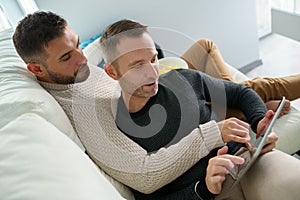 Gay couple consulting their travel plans together with a digital tablet.