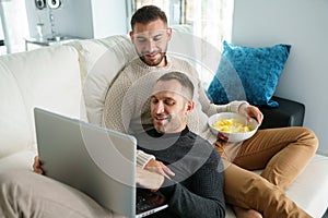Gay couple consulting their travel plans together with a laptop.