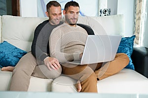 Gay couple consulting their travel plans together with a laptop.