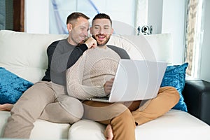 Gay couple consulting their travel plans together with a laptop.