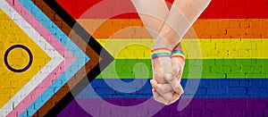 gay couple hands with over progress pride flag