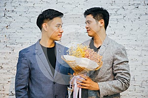 Gay couple holding a bouquet of flowers, ready to give to his partner for special occasions or wedding proposal.