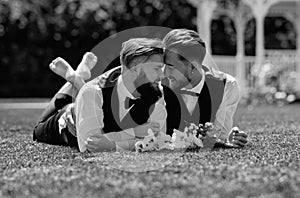 Gay couple laying on grass on wedding day. Married LGBT couples celebrate a romantic wedding ceremony together with a