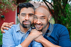 Gay couple looking at camera and holding hand in table outside