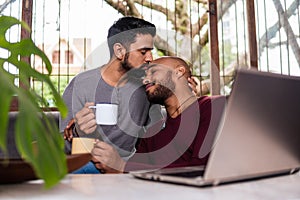 Gay couple moment, enjoying a cup of coffee, kiss the forehead in the couch