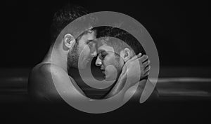 Gay couple relaxing in swimming pool. LGBT. Two young men kissing and hugging. Black and white portrait