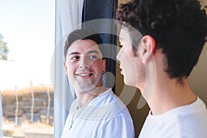 Gay couple sharing a special moment in the morning by the window. Homosexual romantic tenderness.