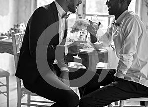 Gay Couple Sitting Talking with Wine Glasses Together