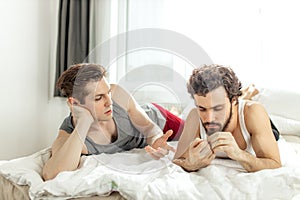 Gay couple talking on bed at home