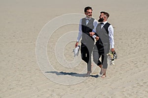 Gay couple together in love. Two gays in feeling love during wedding ceremony. Gay grooms walking together on sea beach