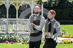 Gay couple wedding with champagne splash. Gay couple open sparkling wine.