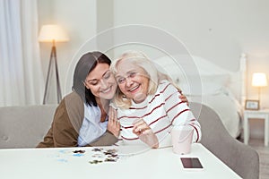 Gay elder woman and caregiver gathering puzzle