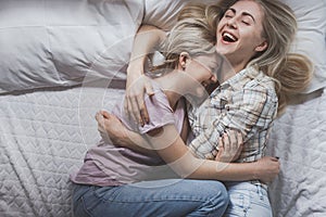 Gay lesbian couple of young girls are lying in bed laughing and cuddling, top view. Concept of love, gay marriage and pride