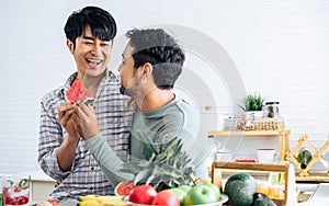 Gay LGBT sweet Asian couple wearing pajamas, smiling with happiness and love, eating, feeding watermalon, healthy fruits for