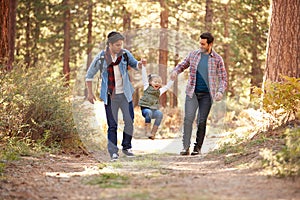 Gay Male Couple With Daughter Walking Through Fall Woodland