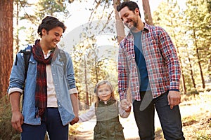 Gay Male Couple With Daughter Walking Through Fall Woodland