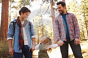 Gay Male Couple With Daughter Walking Through Fall Woodland