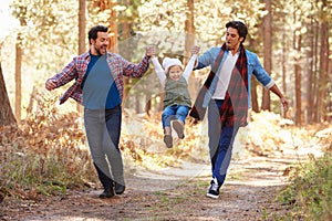 Gay Male Couple With Daughter Walking Through Fall Woodland