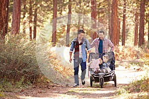 Gay Male Couple Pushing Children In Buggy Through Woods