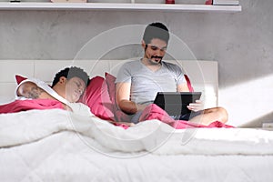 Gay Man Playing Video Game With Partner Sleeping