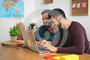 Gay men couple using laptop in living room at home