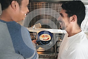 Gay Men Eating Breakfast Cooking Eggs In Home Kitchen