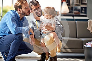 Gay parents with child in store for household