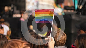 Gay person wave little rainbow flag. People crowd celebrate LGBT pride festival.