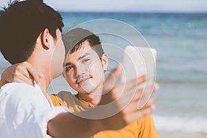 Gay portrait young couple smiling taking a selfie photo together with smart mobile phone at beach