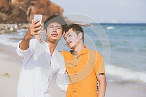 Gay portrait young couple smiling taking a selfie photo together with smart mobile phone at beach