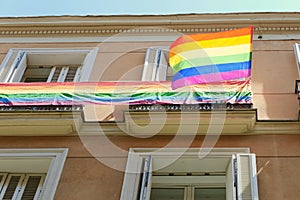 Gay pride flag backlit by sun on the facade of building downtown Madrid, Spain in lgbt friendly district Chueca