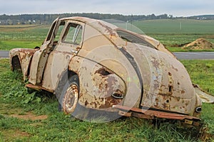 GAZ M20 Pobeda car dented, rusty and with the hood torn off in the field