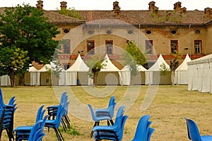 Gazebo in the castle park. Brick barracks built for defensive purposes by the Savoy. Stacked blue chairs in the park