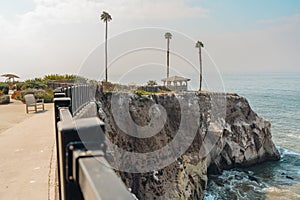 Gazebo on a cliff top, and walkway from hotel to the gazebo, and beautiful Pacific ocean with cloudy sky in the background,