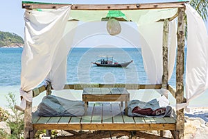 Gazebo for relaxing with white curtains on tropical sand beach near blue sea water on island Koh Phangan, Thailand