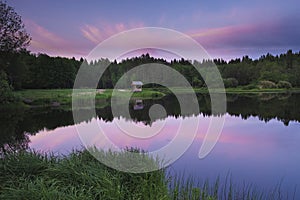 Gazebo on the shore of a forest lake at sunset,