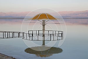 Gazebo for sun protection reflected in Dead Sea water at sunset photo